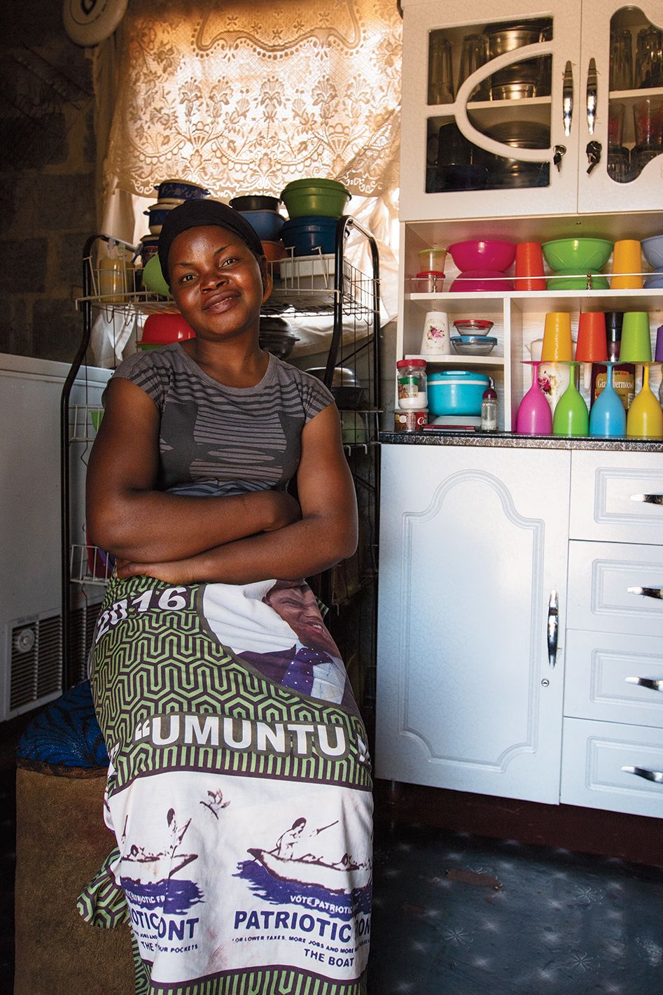 Lucy sits in her kitchen near a hutch filled with colorful dishware.