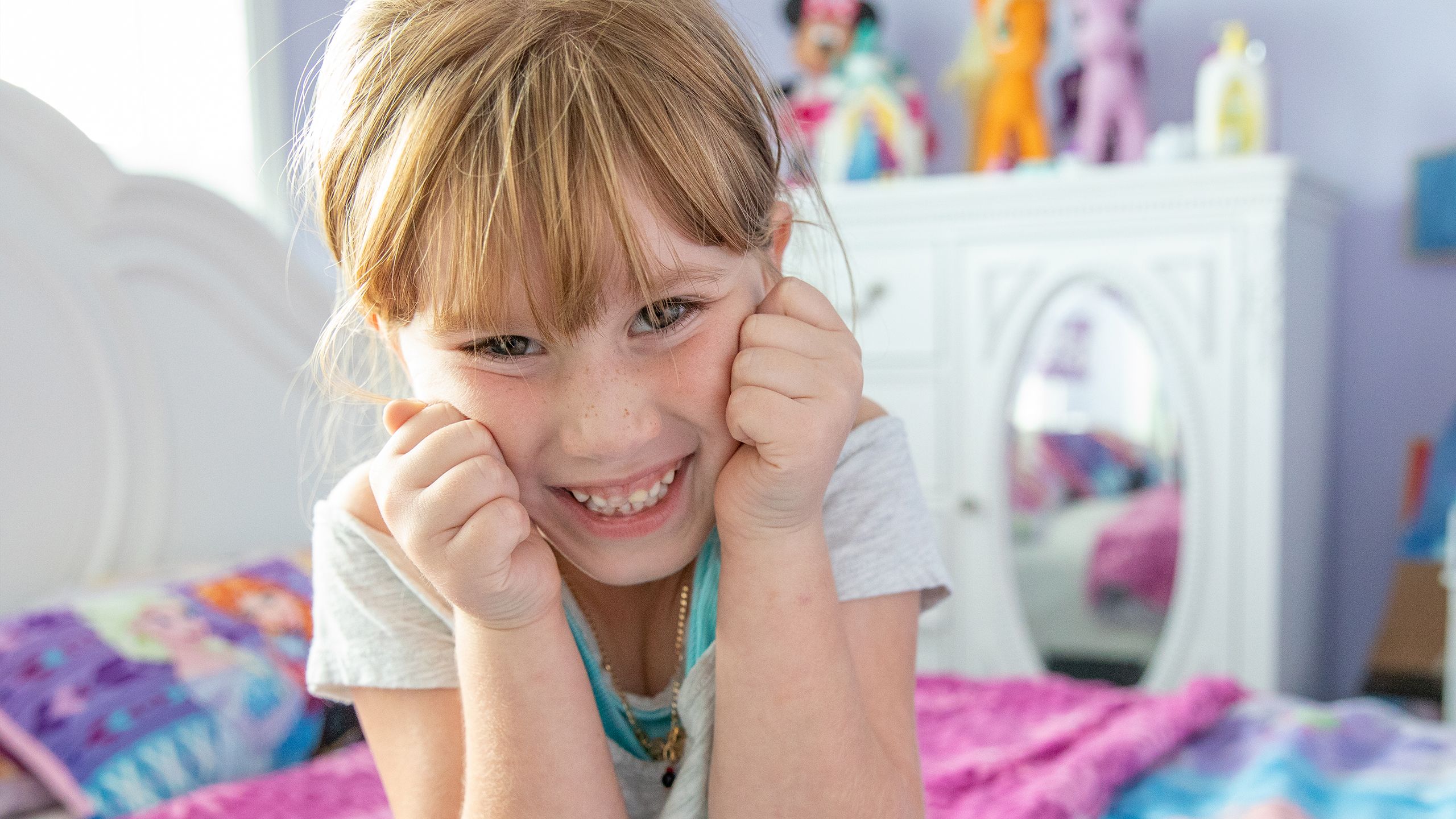 Samantha beams excitedly in her colorfully decorated bedroom.