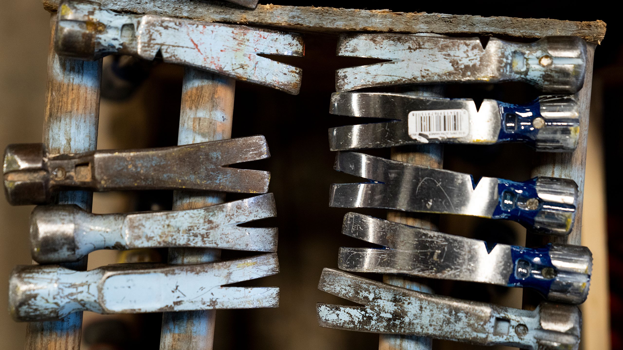 Worn hammers lined up in a wooden rack.