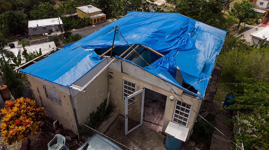Aerial view of Joan Antonio's house, blue tarps covering the entire roof area and blowing back in the wind.