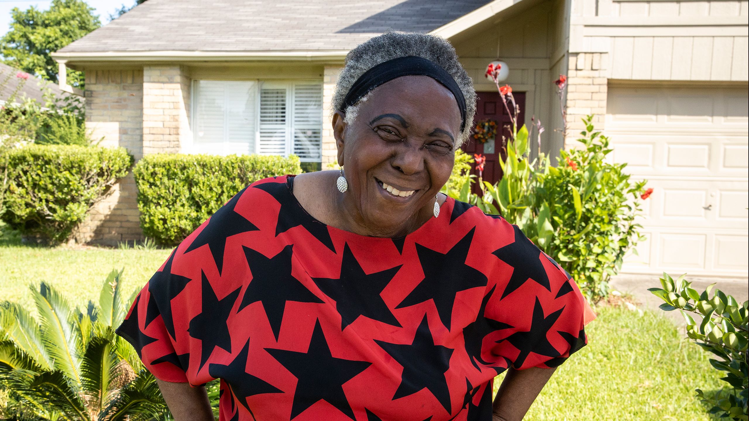 Collette smiles in front of her repaired Habitat home.