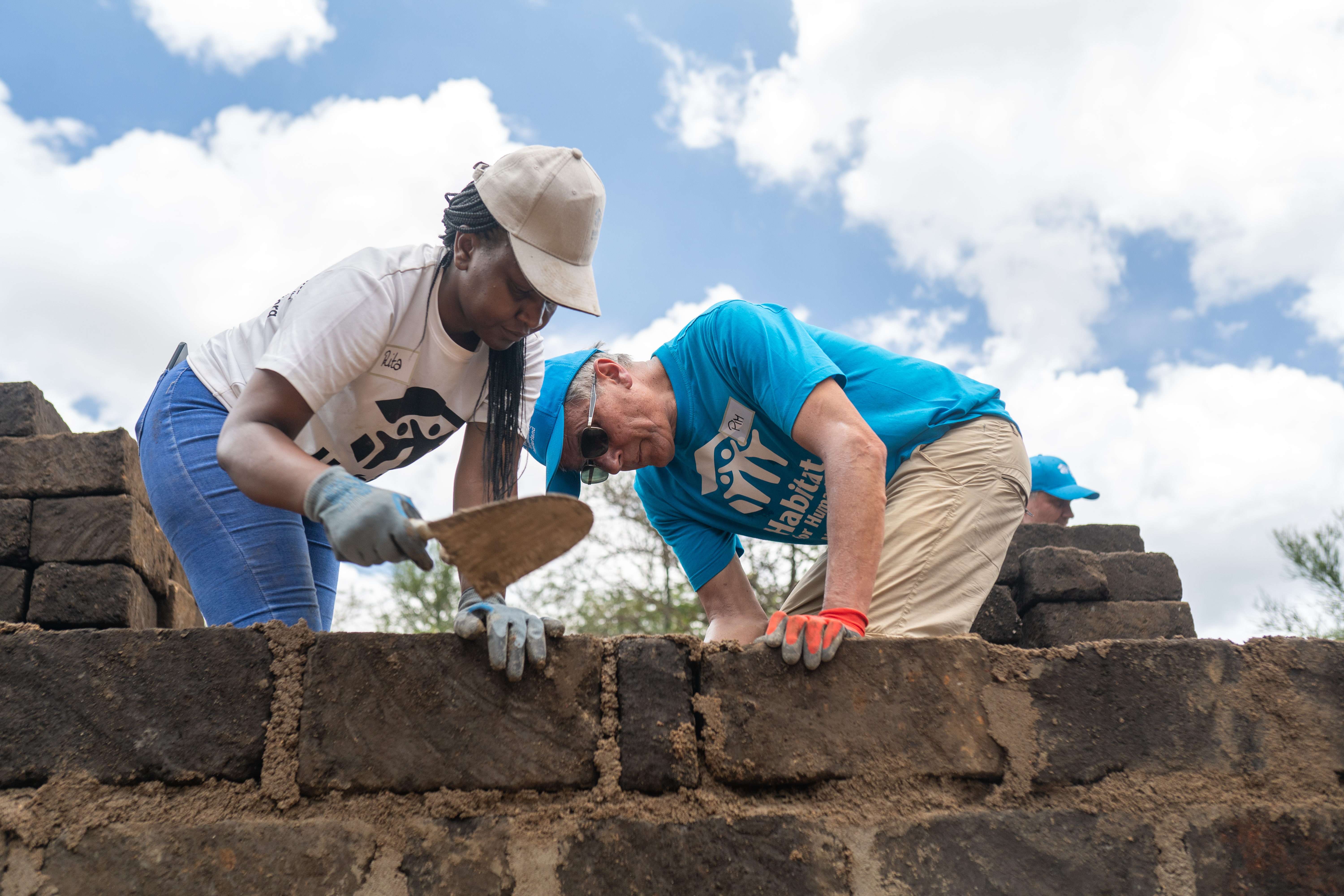 Two people work on building a wall.