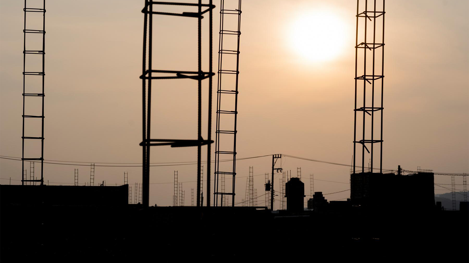 Rigging and ladders on the roof of a building back lit against the sun so that they are in shadows.