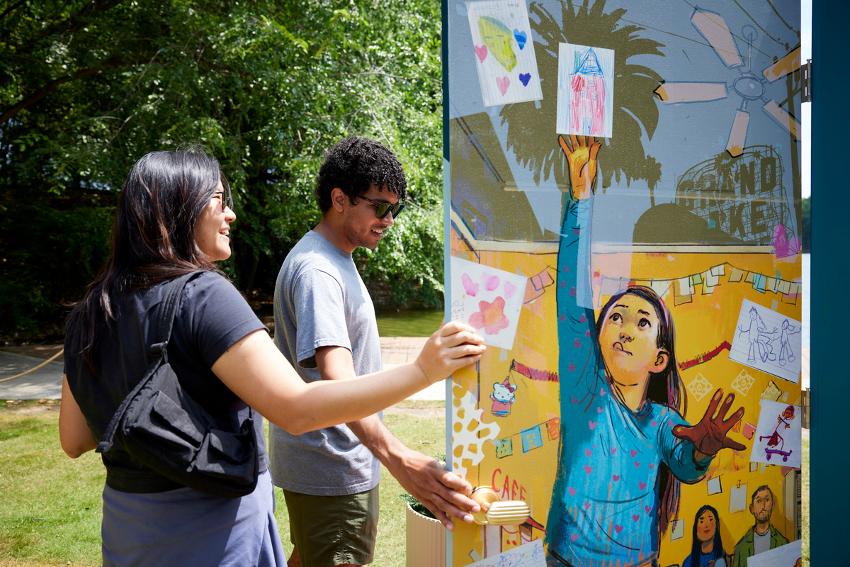A couple interacts with one of the doors in the Let's Open the Door pop-up exhibit at Piedmont Park in Atlanta, Georgia.