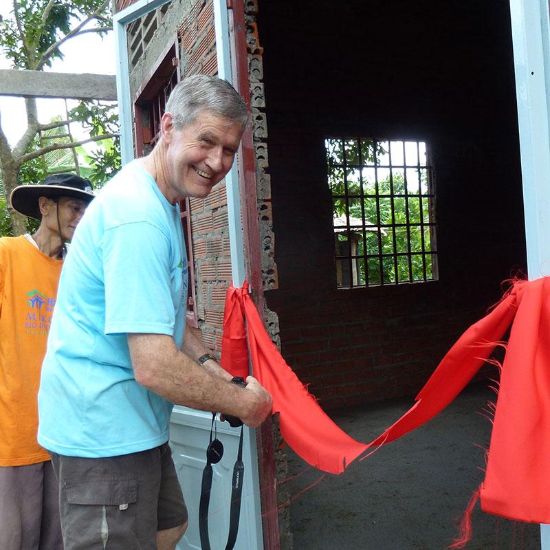 Warren Jack from New Zealand cutting the ribbon during a home dedication in Vietnam