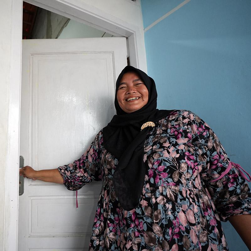 Komariyah opening the door to her new home in Tanjung Kait fishing village, Indonesia