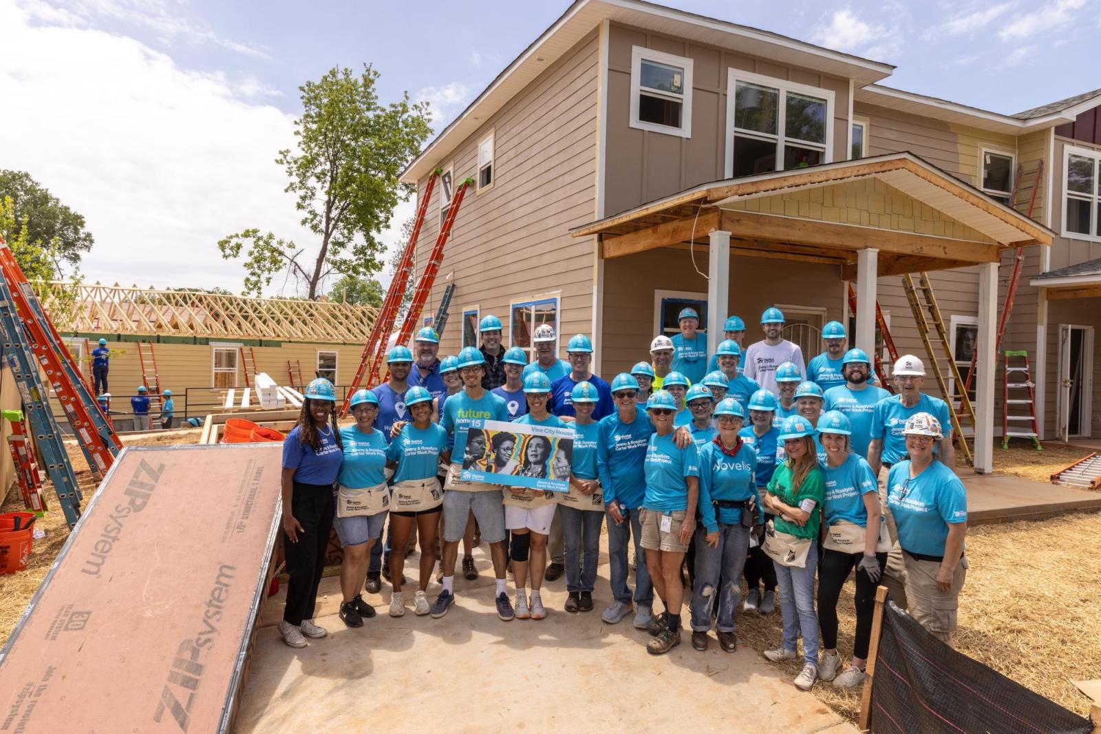 House 15 volunteers posing in front of house on build site.