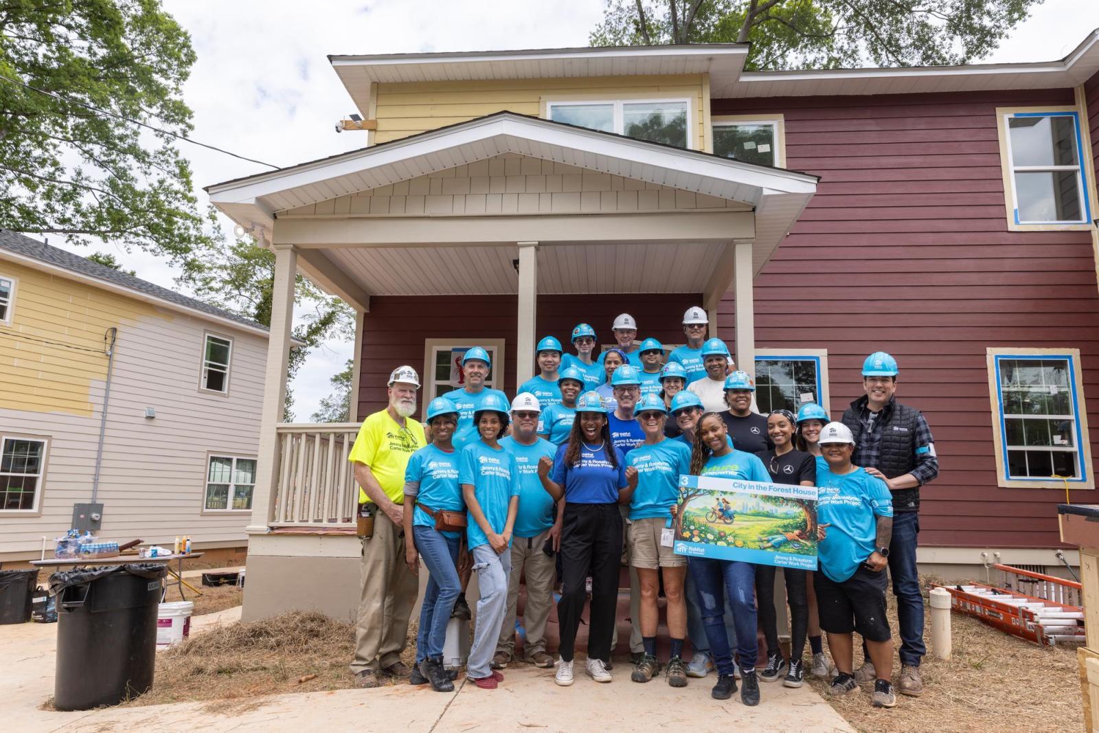 House 3 volunteers posing in front of house.