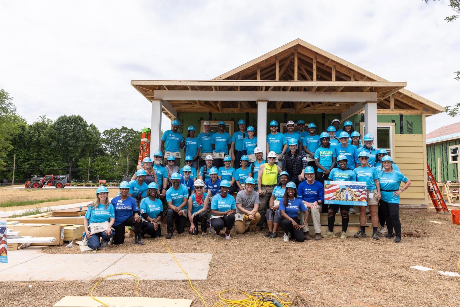 House 5 volunteers posing in front of the house they're building.