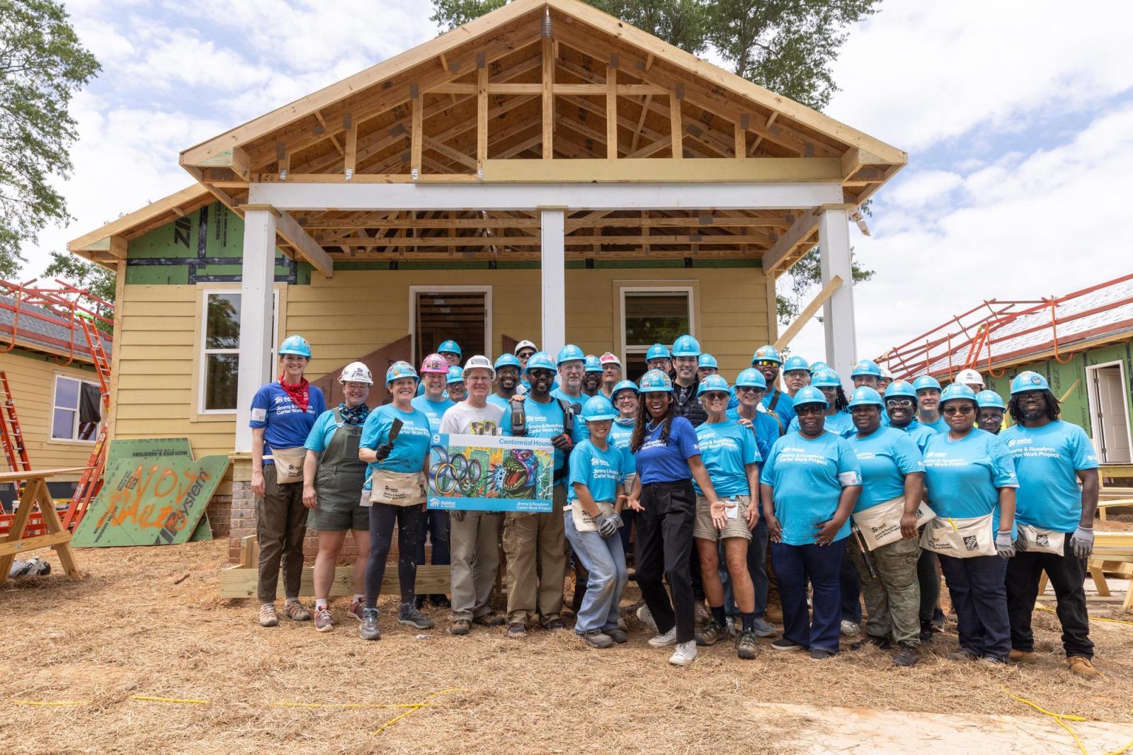 House 9 volunteers posing for group photo in front of house.