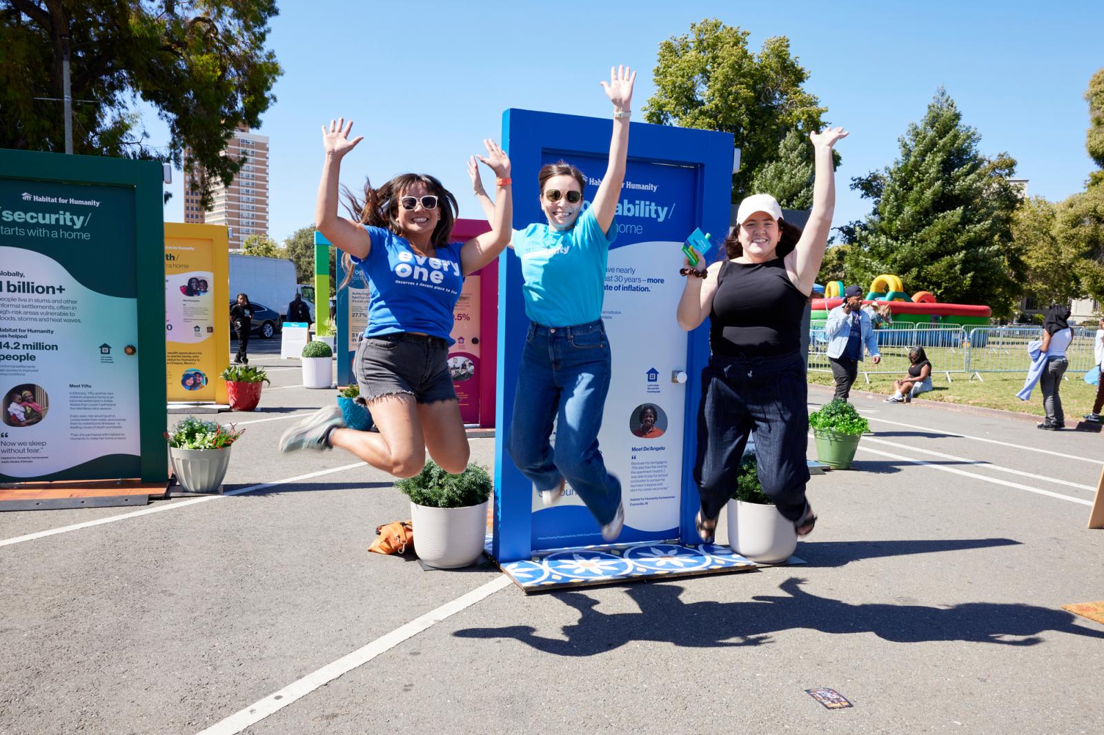 Three women jumping in the air excited in front of illustrated doors.