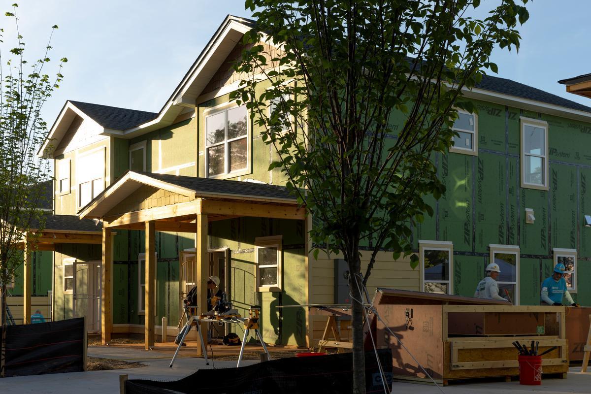 Partially-constructed duplex with green insulation. Volunteers are on site working.