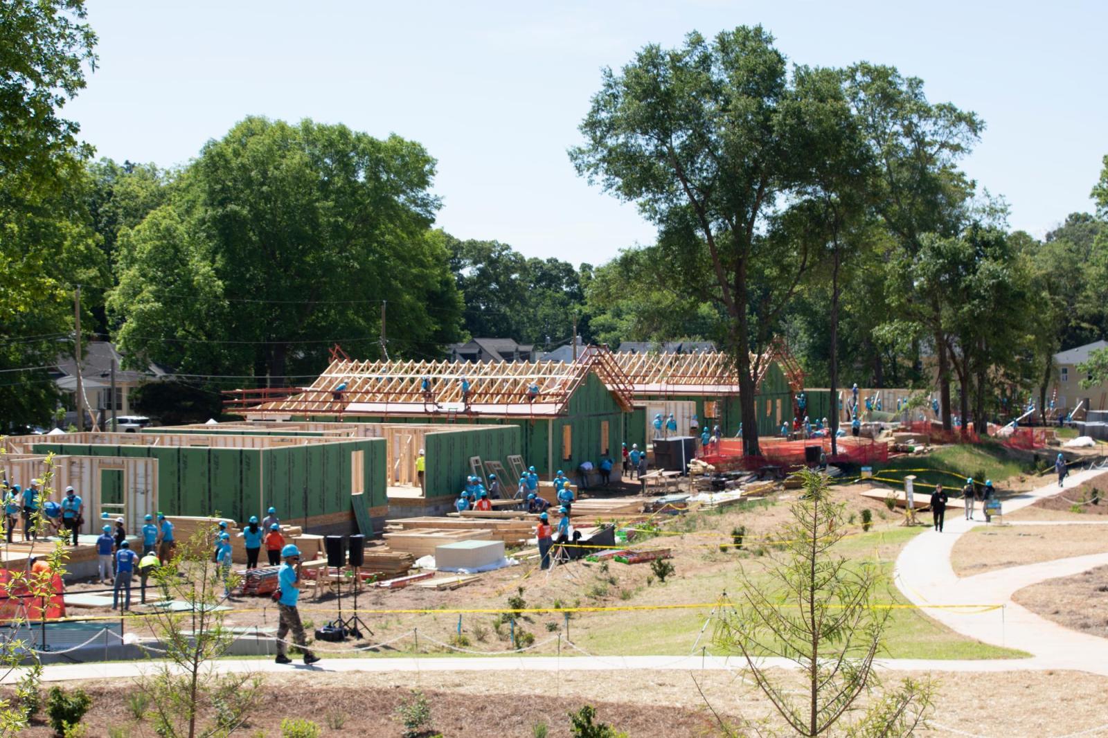 Houses under construction at the 2026 Carter Work Project. The closes house has no roof and there are volunteers walking around the site.