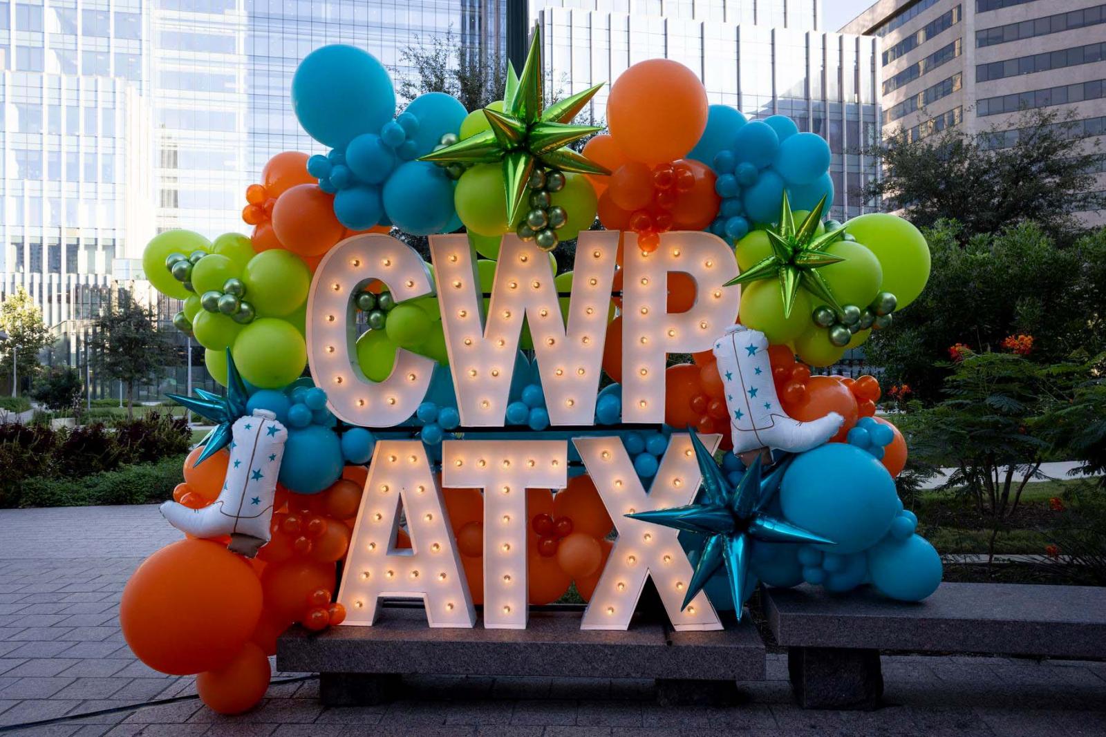 White marquee letters spelling out CWP ATX are surrounded by a large orange, blue and green balloon display.