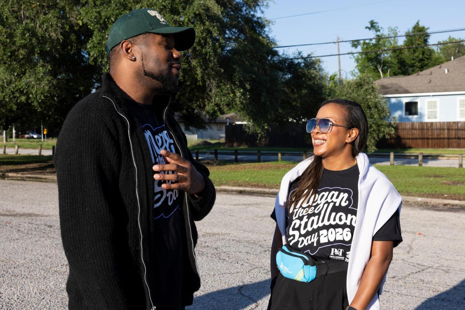 Two volunteers wearing black shirts smile as they discuss plans to tackle a build site for Megan Thee Stallion Day.