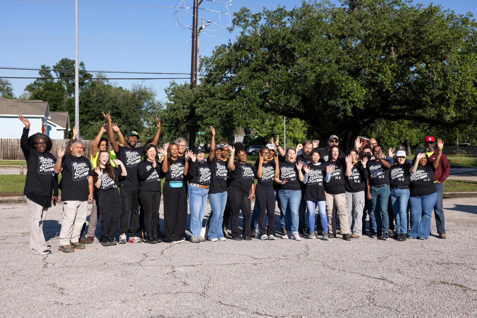 A group of volunteers in black t-shirts stand in a group and smile. 
