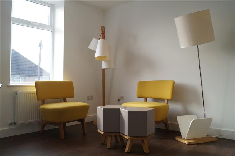 A newly refurbished apartment living space with freshly painted white walls, wood flooring, and modern furniture.