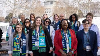 Group of men and women posing outside in front of the Capitol building and snow.
