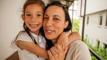Young girl and her mother hugging.