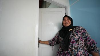 Komariyah opening the door to her new home in Tanjung Kait fishing village, Indonesia