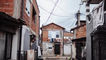 View of urban alleyway between brick and concrete buildings with powerlines overhead.