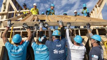 CEO Build attendees volunteer together as they lift a wooden frame at the Carter Work Project build site, October 2024. 