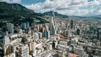 Urban Bogota, Columbia, with highrise buildings against a backdrop of mountains and a blue sky full of fluffy, white clouds.