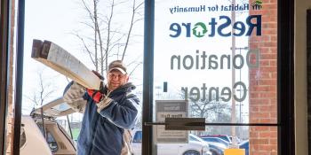 Man carrying lumber he wants to donate into a Habitat ReStore. 