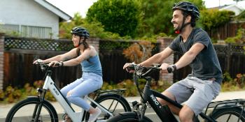 Woman and man riding a bikes with helmets on. 