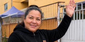 Mujer frente a edificios que con su liderazgo comunitario ayudó a ampliar