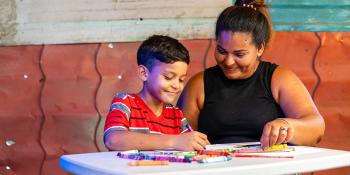 Un niño dibuja, su madre está al lado y lo observa