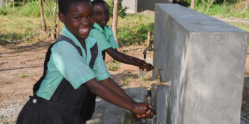 School children washing their hands at a hand washing station in school