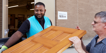 Man and ReStore staff member bring donated and used door into ReStore