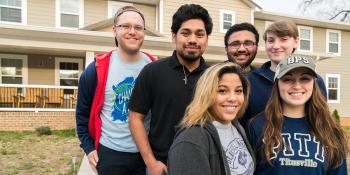 Six student volunteers standing in a group and smiling after participating in a Habitat volunteer opportunity.