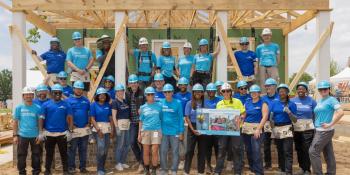 Group of volunteers posing in front of framed-out house on site of 2026 Carter Work Project.
