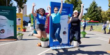 Three women jumping in the air excited in front of illustrated doors.