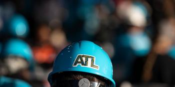 Back of a volunteer's head wearing a blue hard hat with an "ATL" sticker on it.
