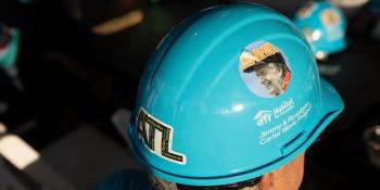 Overhead shot of a volunteer wearing a blue Habitat hard hat with a large "ATL" sticker on the back and a sticker of Jimmy Carter on the side. 