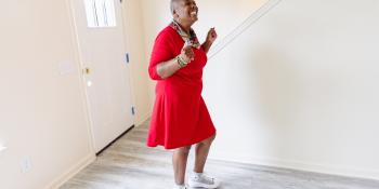 A woman in a red dress smiling in excitement inside her new house.