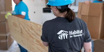 Carter Work Project volunteers carrying a sheet of plywood.