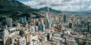 Urban Bogota, Columbia, with highrise buildings against a backdrop of mountains and a blue sky full of fluffy, white clouds.