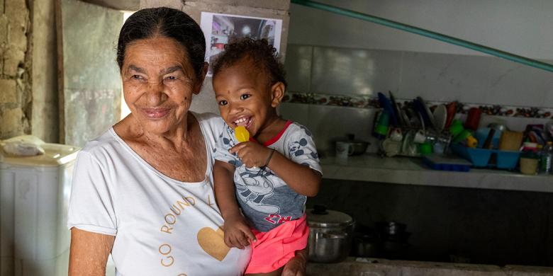 Isabel María llegó al barrio Olaya Herrera, en Cartagena, hace 33 años tras ser desplazada por la violencia. Con esfuerzo propio adquirió su vivienda y, luego de separarse, asumió la crianza de sus dos hijos y dos nietos. Hoy se siente en paz al ver a su nieto gatear con seguridad sobre el nuevo piso de concreto instalado gracias a 100 mil pisos para jugar. 