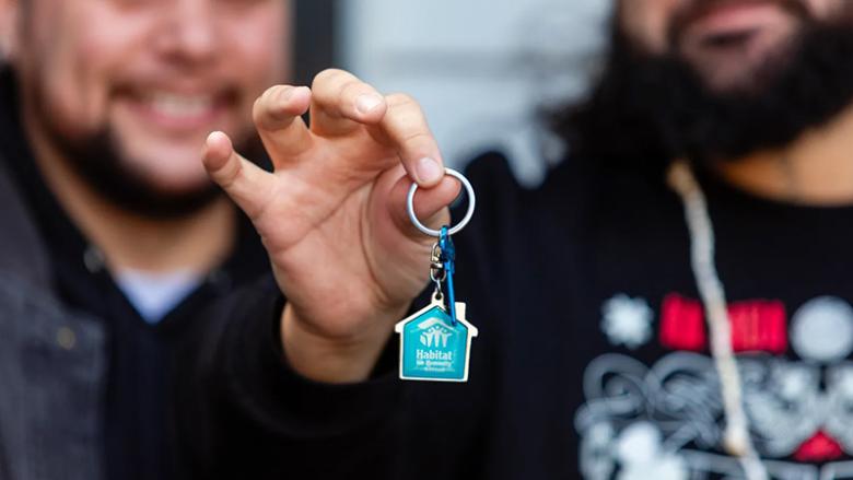 A person holding a key at home dedication in New Zealand