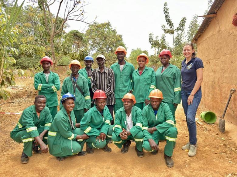A group of artisans in green overalls pictured in a rural setting
